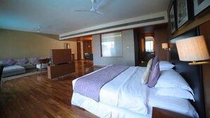 A hotel room with a large bed, a sofa, a desk, and a ceiling fan. - Club Mahindra Kensville Golf Resort (Bavla)