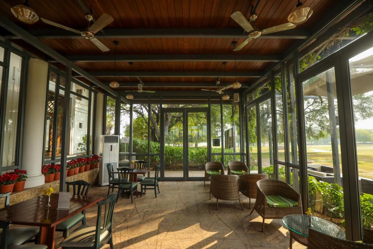 A covered outdoor seating area with tables and chairs, large windows, and ceiling fans.