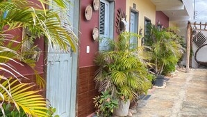 A building with numbered doors, potted plants, and a stone-paved entrance. - Bru&Mar Pousada Parnaíba (Parnaíba)