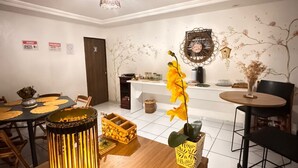 A dining area with a wooden table, a decorative lantern, and a vase with a yellow flower. - Bru&Mar Pousada Parnaíba (Parnaíba)