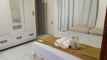 A hotel room with a bed, a wardrobe, a bathroom, and a window with curtains.