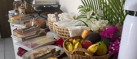 A buffet table with various food items, a coffee machine, and decorative flowers.