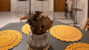 A dining area with a table set with yellow doilies, a decorative vase, and a chandelier. - Bru&Mar Pousada Parnaíba (Parnaíba)