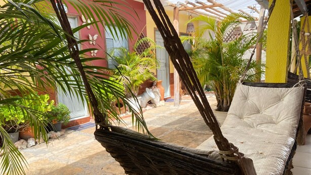 A hammock chair with a cushion, surrounded by potted plants and a tiled floor. - Bru&Mar Pousada Parnaíba (Parnaíba)