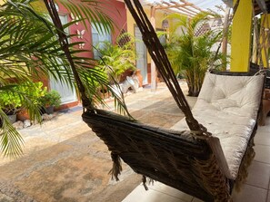 A hammock chair with a cushion, surrounded by potted plants and a tiled floor. - Bru&Mar Pousada Parnaíba (Parnaíba)