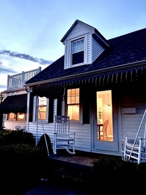 A two-story house with a porch, a small staircase, and a door leading to an interior room. - Charming Seashore Cottage • Gardens Location • Beach Tags Included (Ocean City)