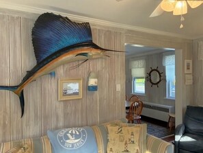 A room with a large fish decoration, a framed picture, and a patterned cushion. - Charming Seashore Cottage • Gardens Location • Beach Tags Included (Ocean City)