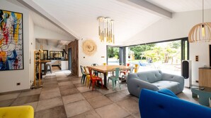 Een ruime woonkamer met een eettafel, kleurrijke stoelen en een grote bank.