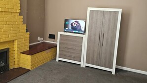 A room with a fireplace, a television, a wardrobe, and a bed. - M4 Victoria Hub 1 (Newport)
