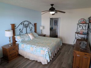 A bedroom with a bed, wooden nightstands, a ceiling fan, and a bedside table with a lamp. - Sonoran Spa W 101 3 Bed 2 Bath (Puerto Peñasco)