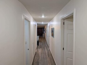 A hallway with white walls, wooden flooring, and white doors. - Sonoran Spa W 101 3 Bed 2 Bath (Puerto Peñasco)