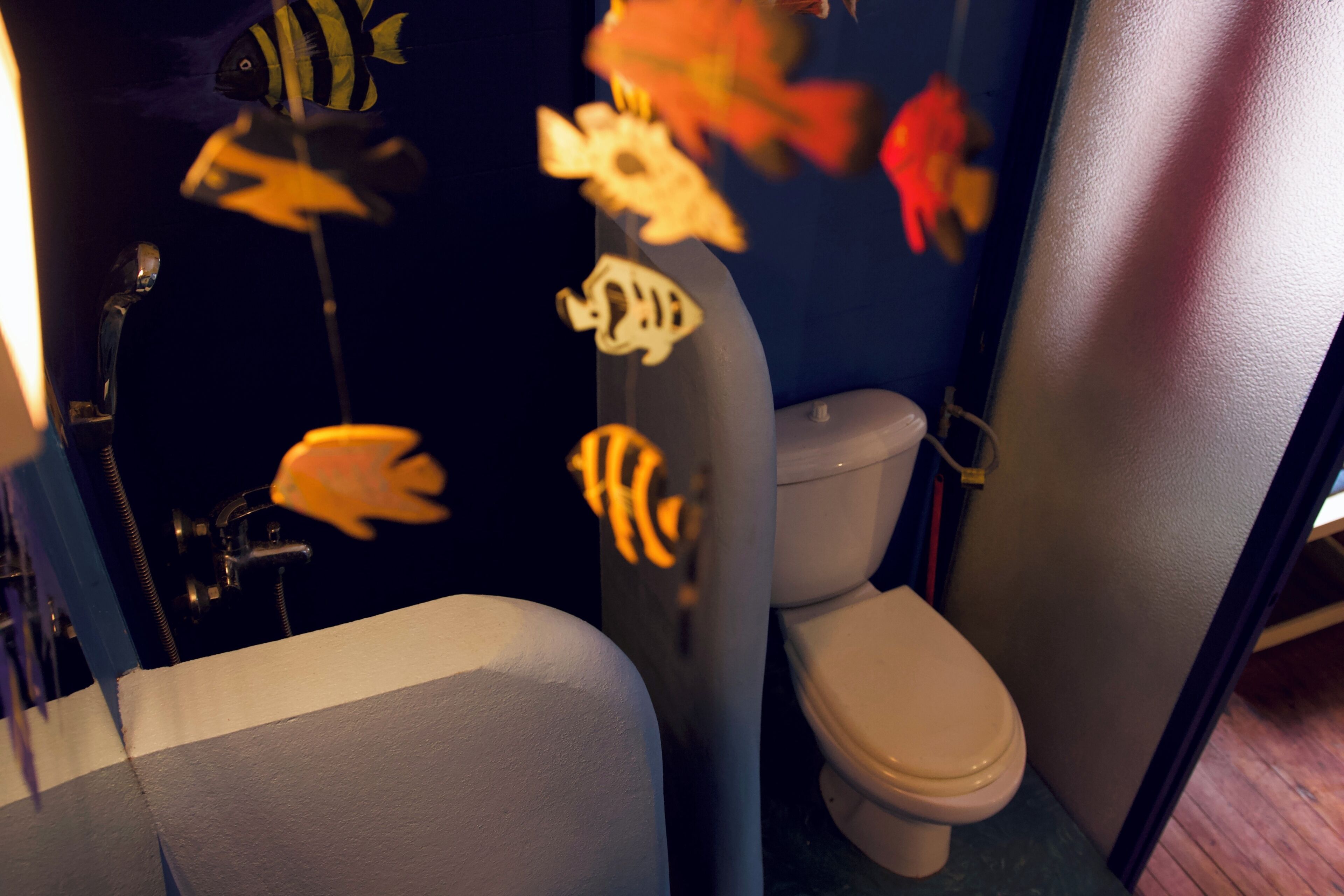 Un baño con inodoro, bañera y pegatinas decorativas de peces en la pared.