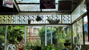A room with a glass partition, a metal railing, and a view of greenery outside. - Le Karthala (Antananarivo)