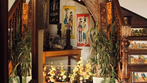 A wooden staircase with a bench, potted plants, and artwork on the walls. - Le Karthala (Antananarivo)