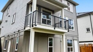 A two-story residential building with a balcony, a garage, and a fenced yard. - Quiet Private Room Victoria - PS5, Fast WiFi, Parking (Langford)