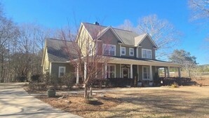 A two-story house with a front porch, a driveway, and a well-maintained lawn.