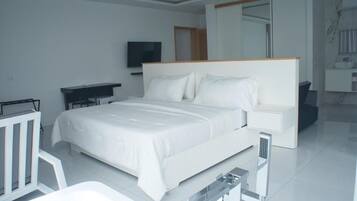 A modern hotel room with a large bed, a desk, a television, and a bathroom with a mirror and sink.
