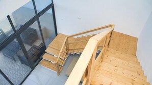 A wooden staircase leading to a room with a glass wall. - The View Hotel CV (Sao Filipe)