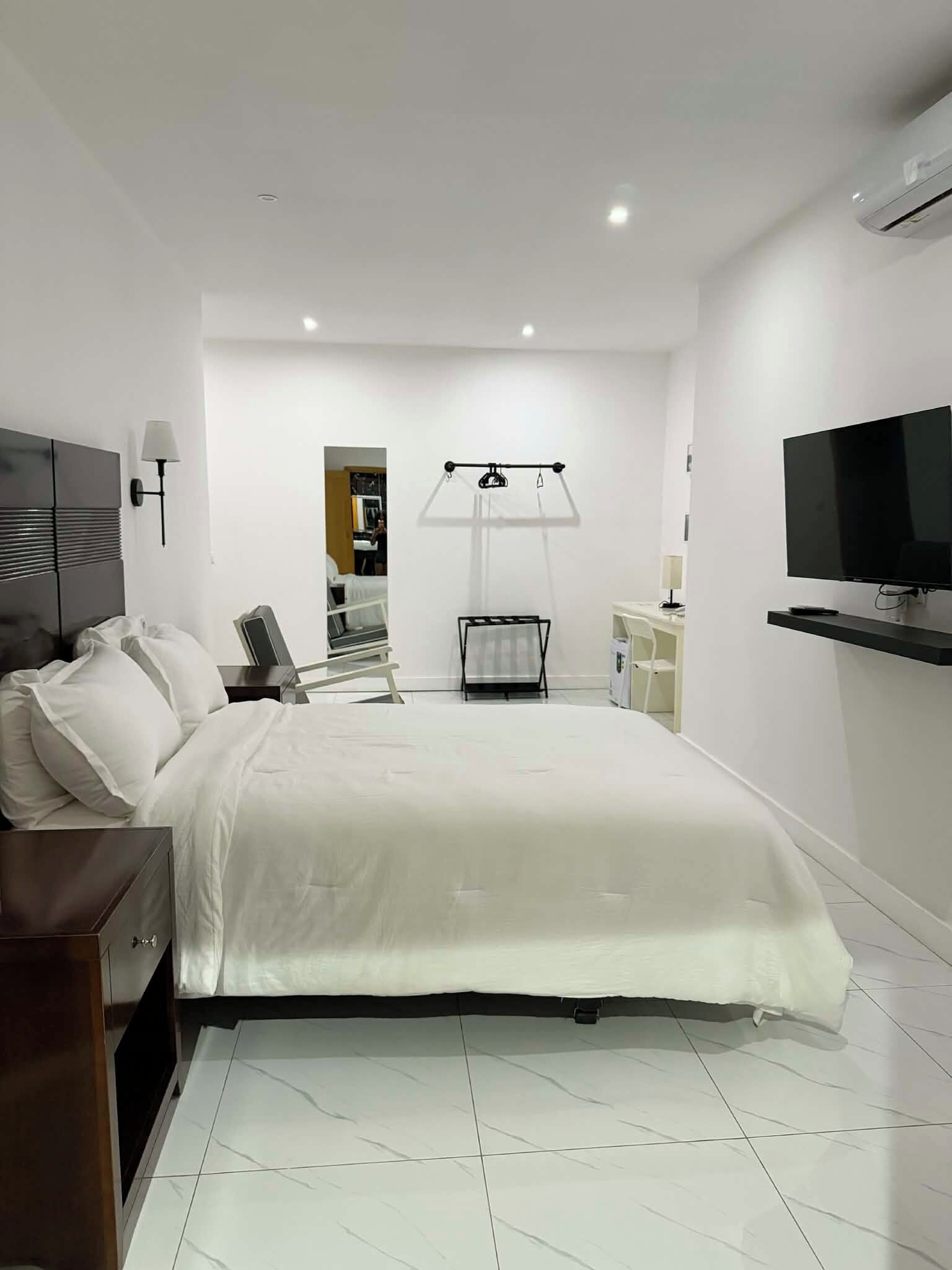 A modern hotel room with a large bed, a TV, a desk, and a chair.