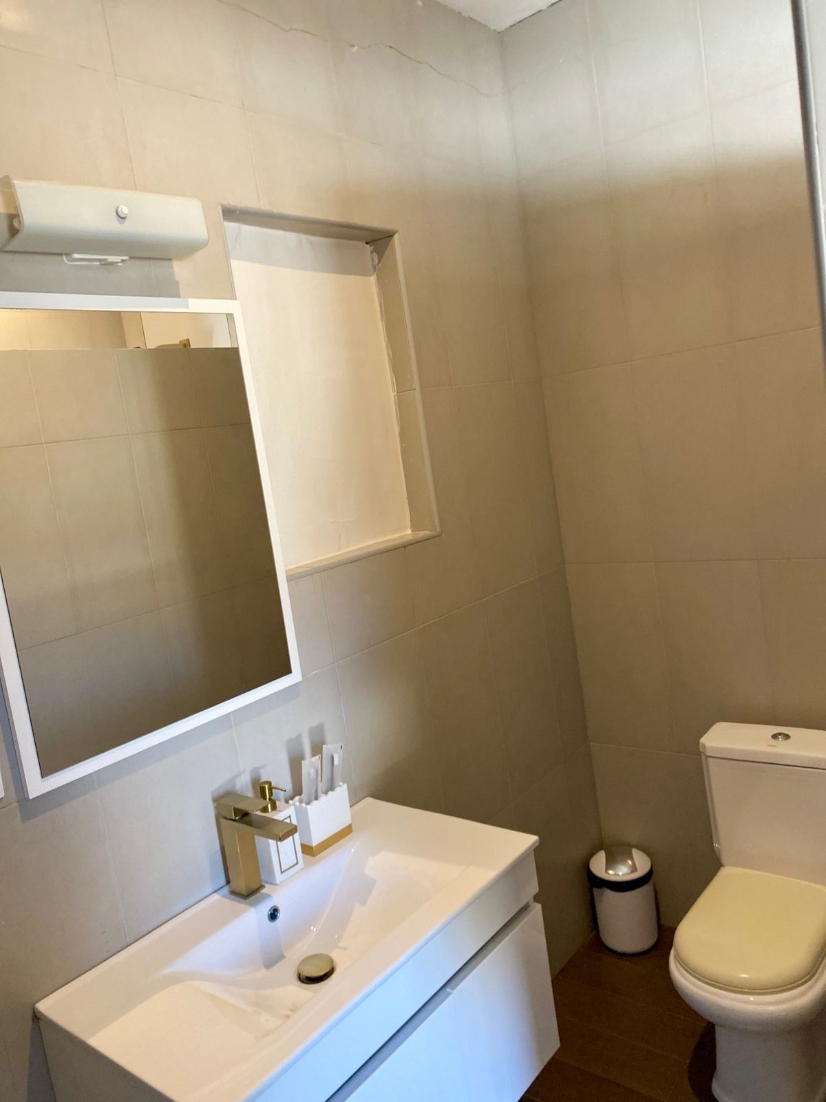 A modern bathroom with a white sink, mirror, and toilet.
