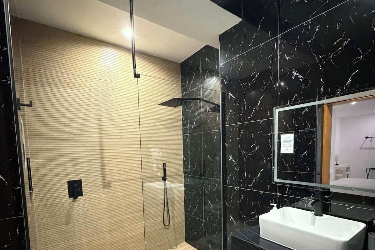 A modern bathroom with a wooden shower enclosure, a large mirror, and a white sink.