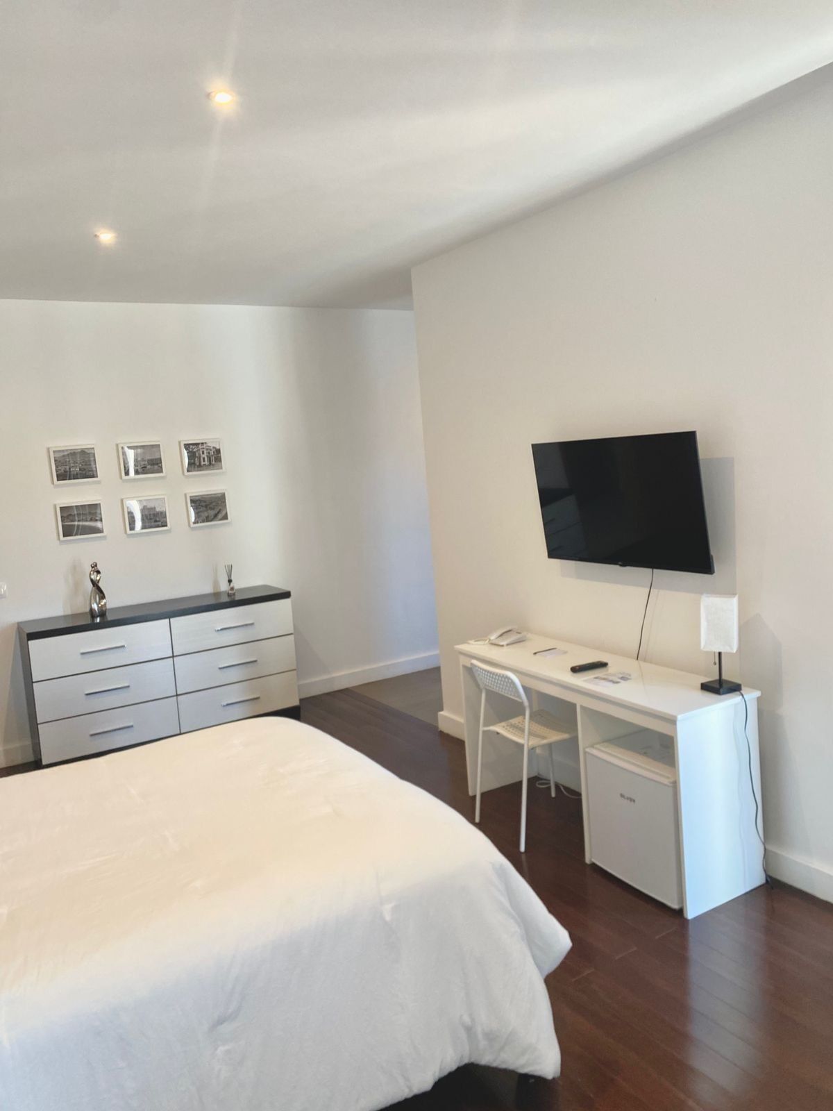 Un dormitorio con cama, escritorio, silla, televisor y cómoda.