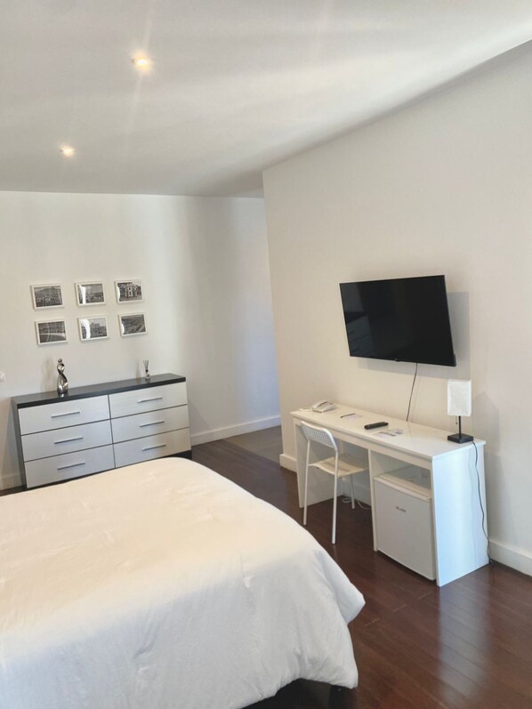 A bedroom with a bed, a desk, a chair, a TV, and a dresser. - The View Hotel CV (Sao Filipe)