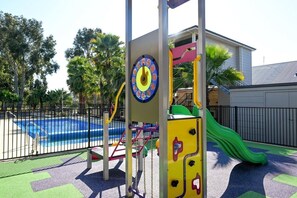 A playground with a slide, climbing structures, and a pool.
