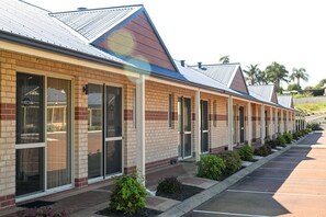 A row of motel rooms with large windows and a brick facade.