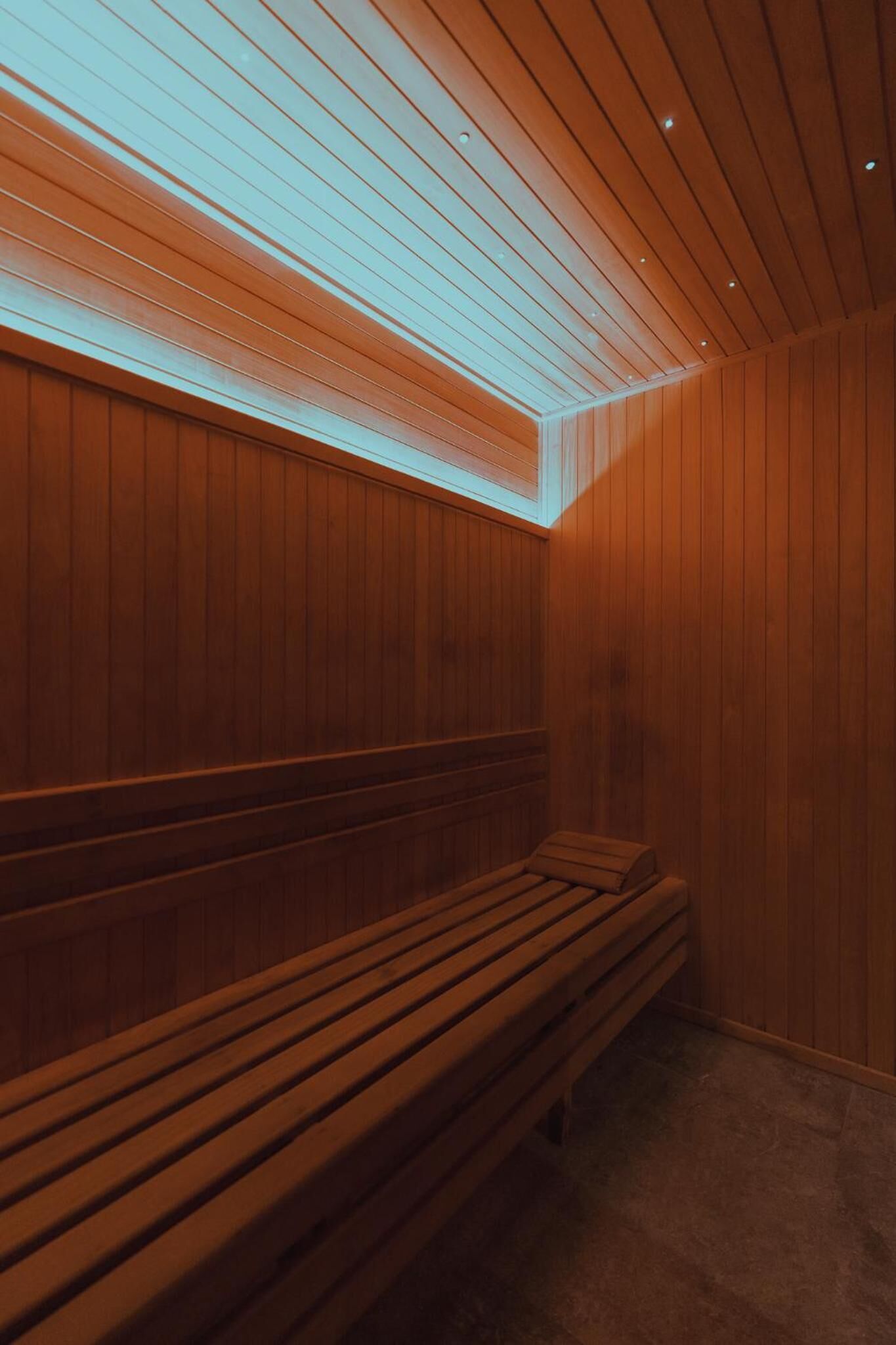 A wooden bench in a room with wooden paneling and a sloped ceiling.