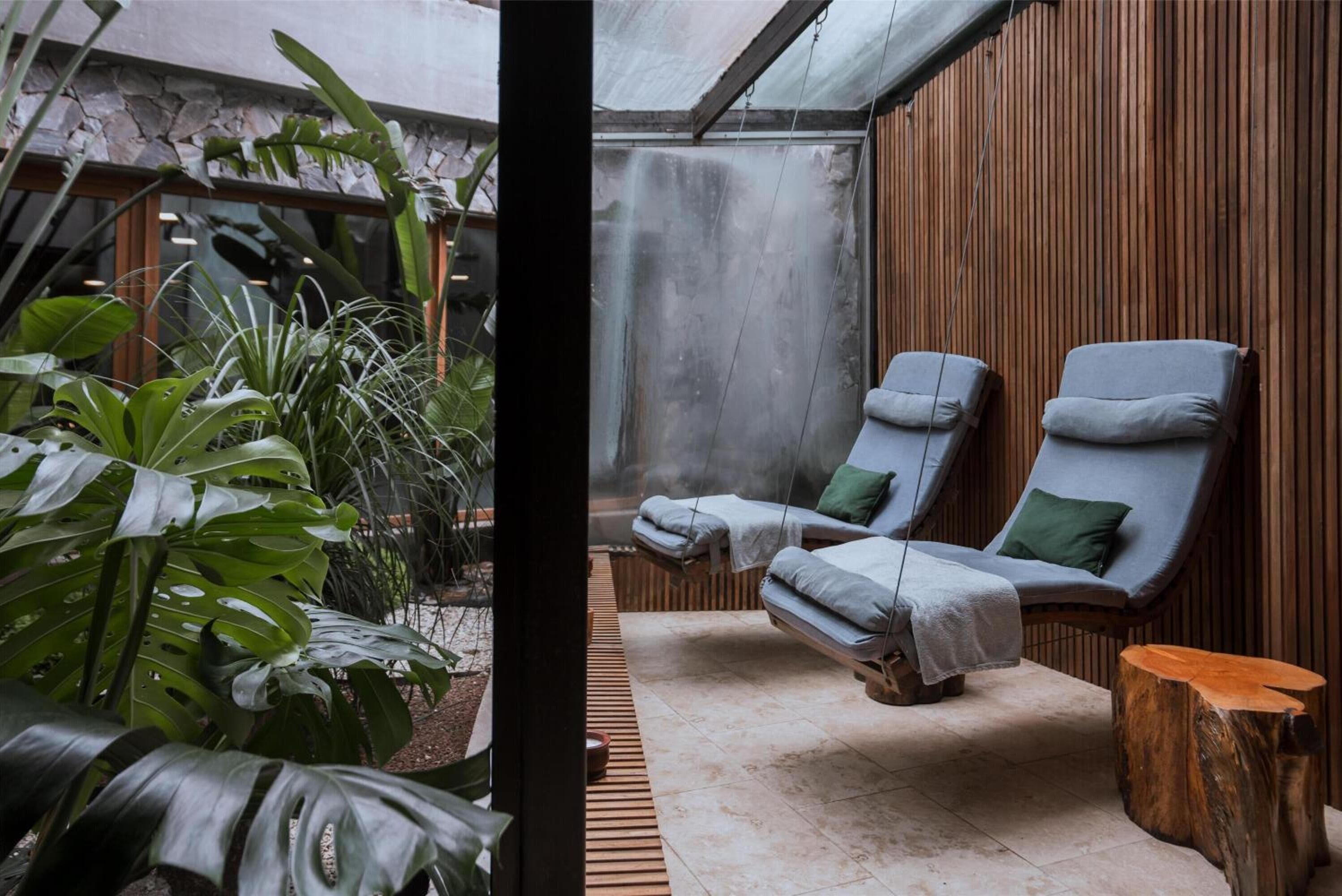 A spa area with two lounge chairs, a stone wall, and tropical plants.