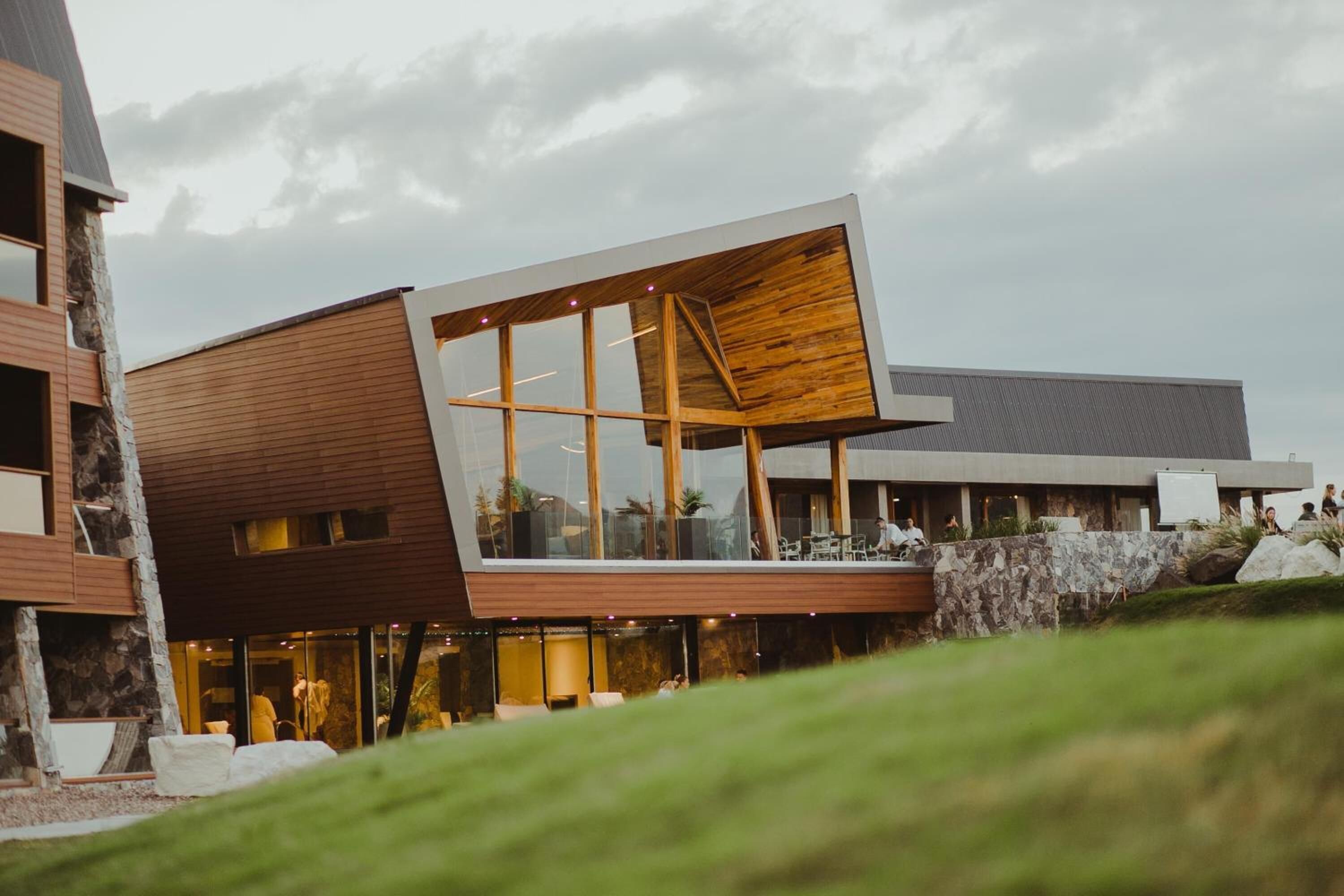 A modern building with a sloped roof, large windows, and a stone facade.