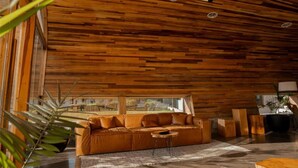 Un intérieur moderne avec un plafond en bois, un canapé, une table basse et une vue dégagée sur l’extérieur grâce à de grandes fenêtres.