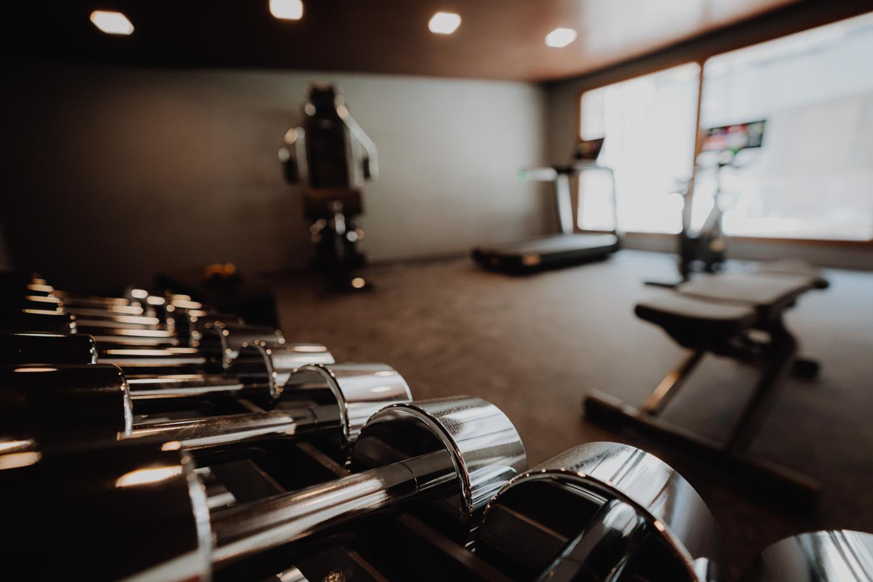 Een fitnessruimte met trainingsapparatuur, een loopband en een raam met uitzicht.