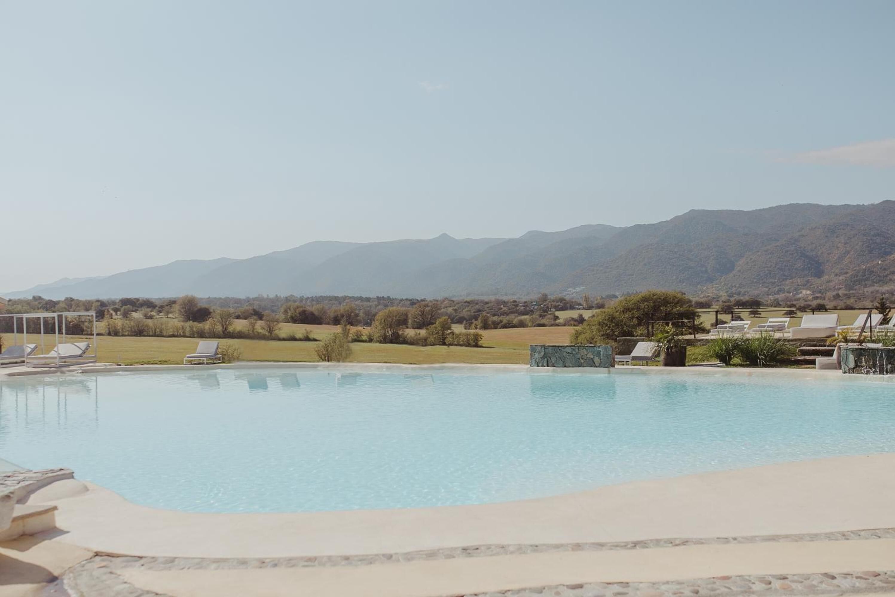 A swimming pool with lounge chairs, a stone deck, and a view of distant mountains.