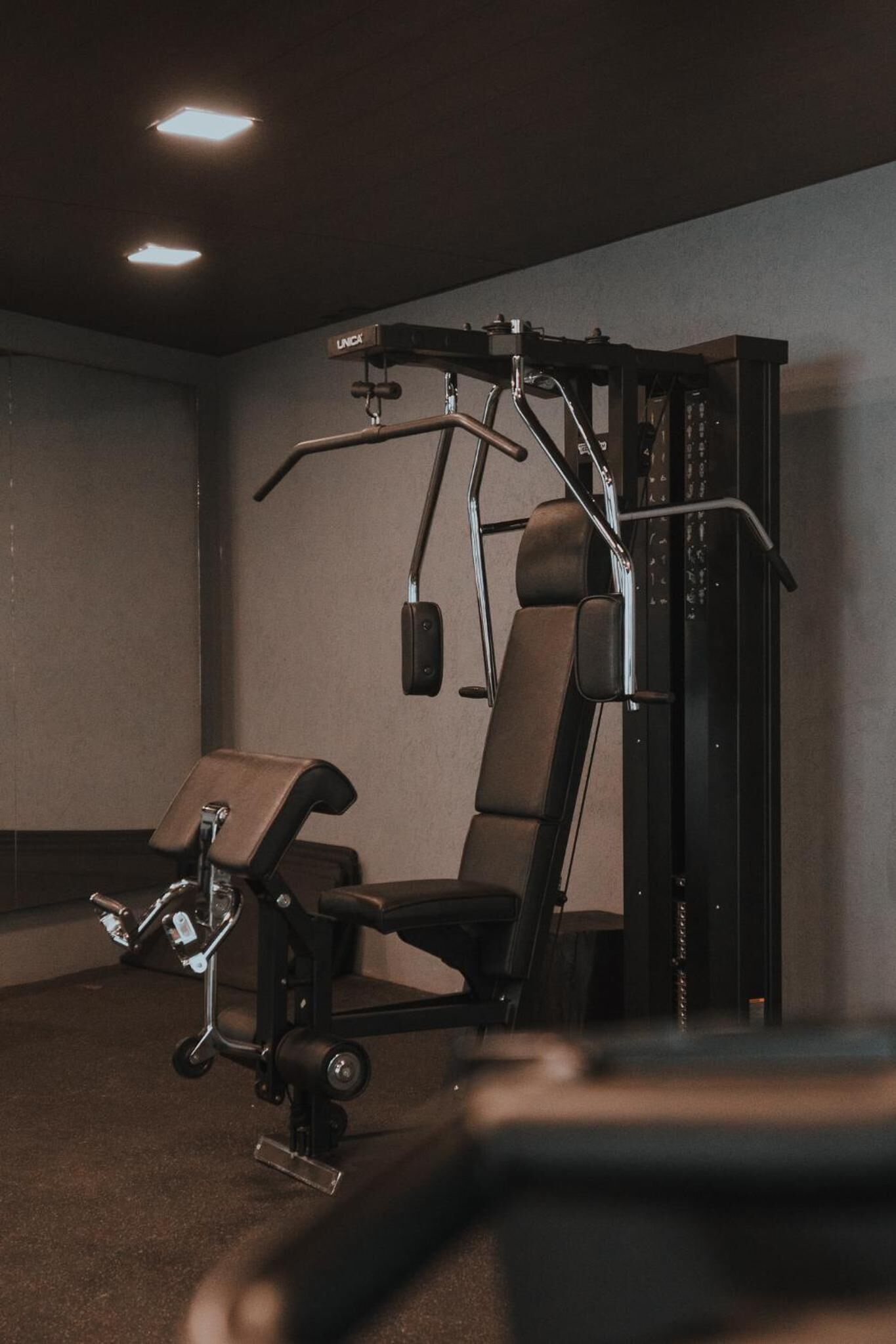 Een sportschool met trainingsapparatuur, een bank en een spiegel aan de muur.