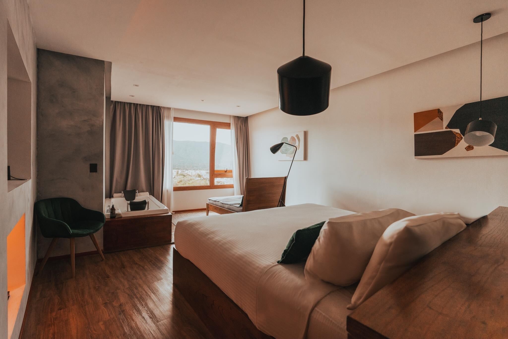 Ett modernt hotellrum med en stor säng, ett skrivbord, en stol och utsikt över omgivningarna.