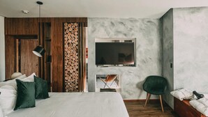 Un dormitorio moderno con una cama grande, un televisor montado en la pared, un panel de pared de madera y una silla verde.