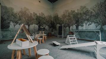 A room with a mural of trees, a whiteboard, and a whiteboard stand.