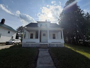 A two-story house with a front porch, a driveway, and a lawn.