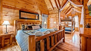 L’intérieur d’un chalet en bois comprend un lit, des tables de chevet, un miroir et un lit superposé.