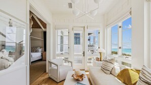 En rummelig opholdsstue med havudsigt, en hvid sofa, et sofabord og en bogreol.