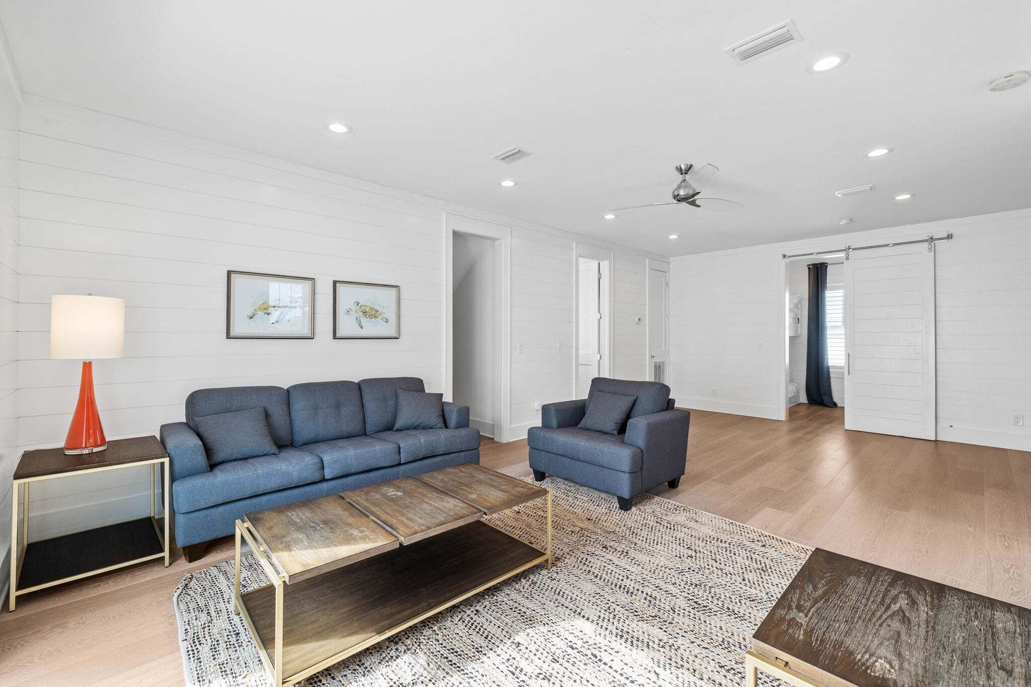 Una sala de estar moderna con un sofá, un sillón, una mesa de centro y una lámpara.