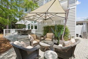 A covered patio with wicker furniture, a table, and a large umbrella.