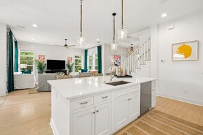 A modern kitchen with a large island, white cabinetry, and pendant lighting.