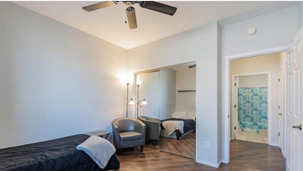 Un dormitorio con dos camas, una silla, un ventilador de techo y un espejo.