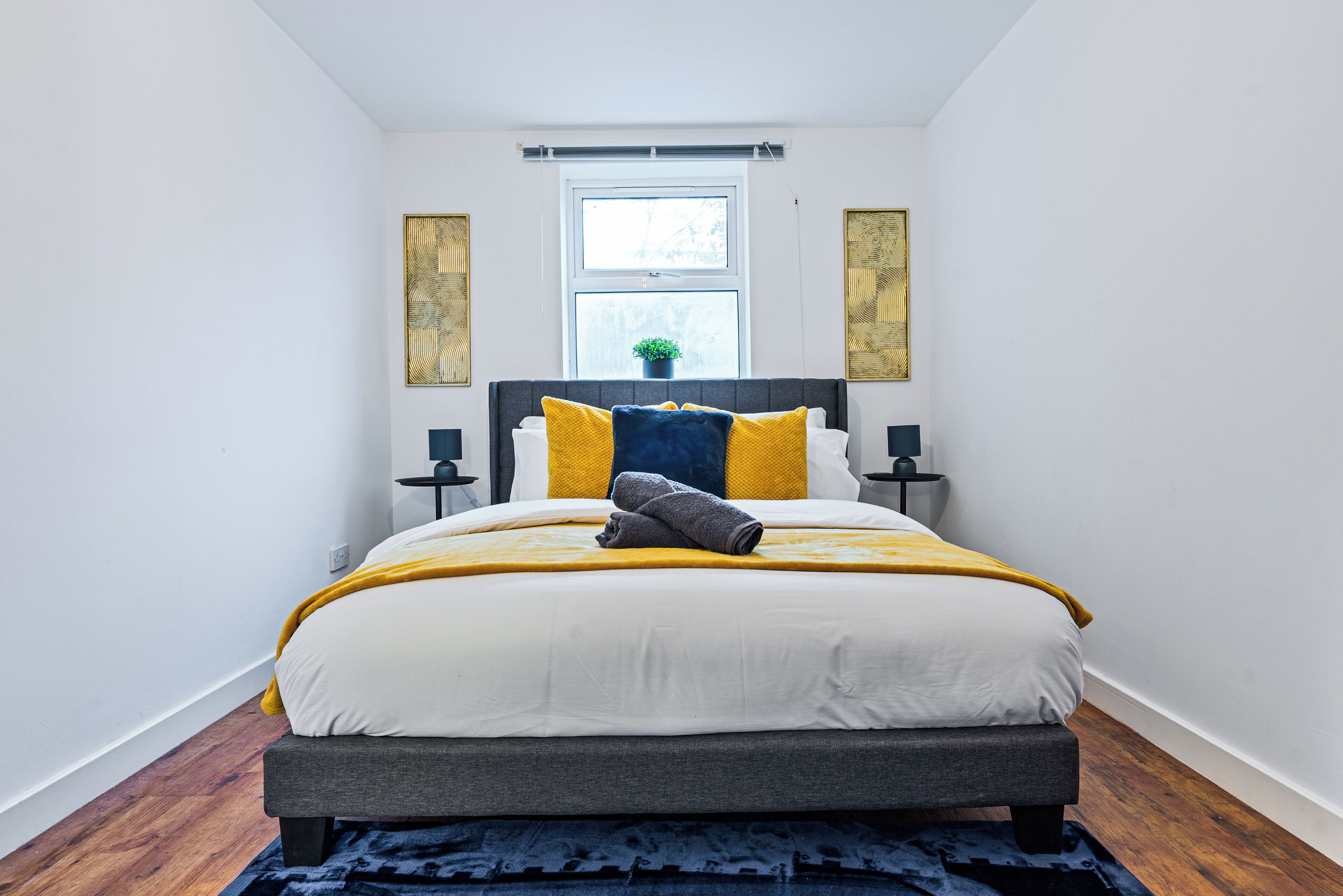 A bedroom with a bed, a window, and two bedside tables.