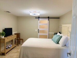 A bedroom with a bed, a desk, a chair, a television, and a sliding door. - Amazing First Floor Condo steps from the Beach w/ breathtaking views - sleeps 6 (Cape Canaveral)