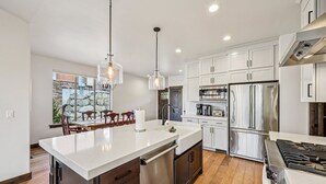 Una cocina moderna con electrodomésticos de acero inoxidable, una isla central e iluminación colgante.