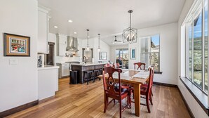 Una cocina amplia con una isla central, piso de madera y ventanas grandes con vistas.